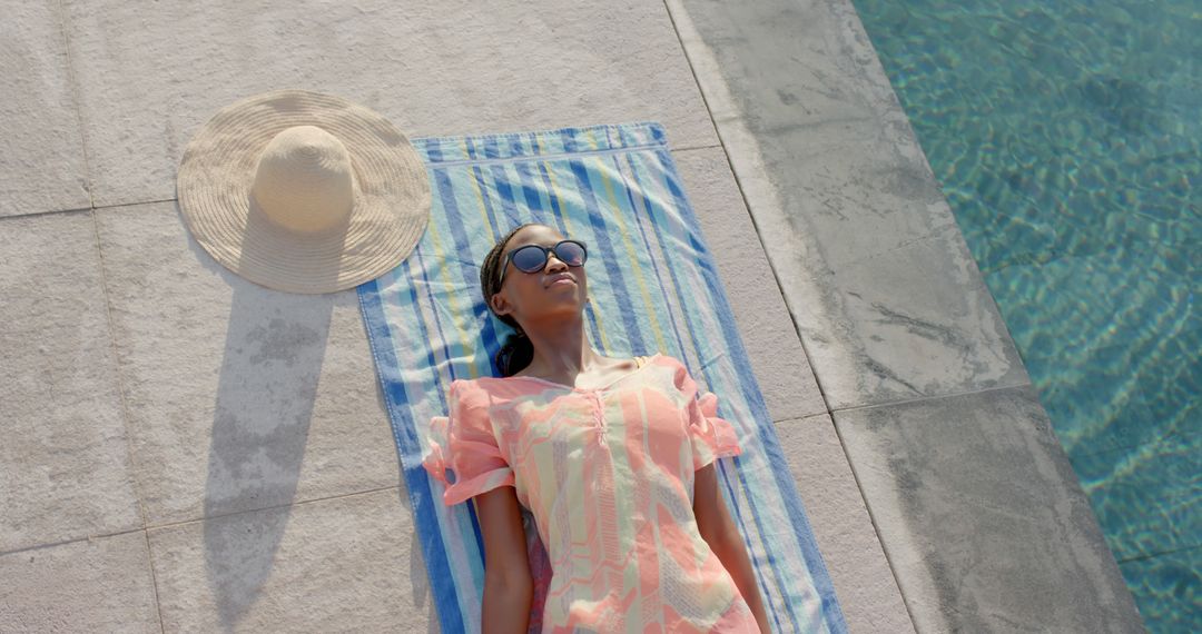 Happy african american woman lying on towel and sunbathing by swimming pool - Free Images, Stock Photos and Pictures on Pikwizard.com