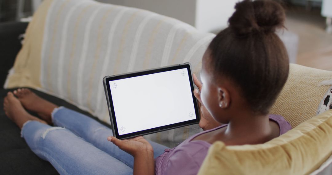 Young Girl Using Tablet on Couch at Home - Free Images, Stock Photos and Pictures on Pikwizard.com