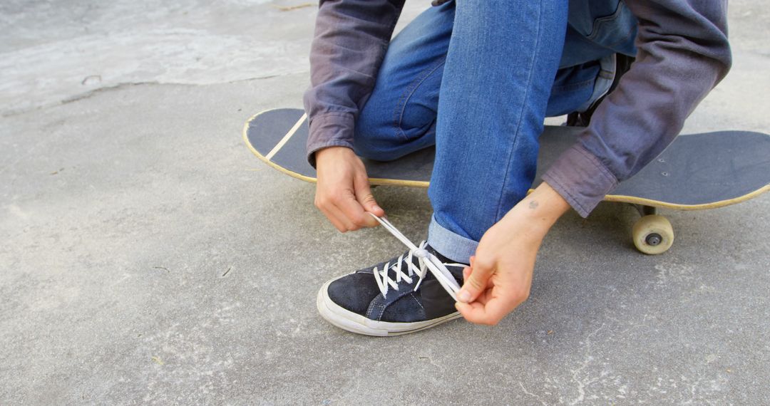 Person Tying Shoe Next to Skateboard on Outdoor Pavement - Free Images, Stock Photos and Pictures on Pikwizard.com