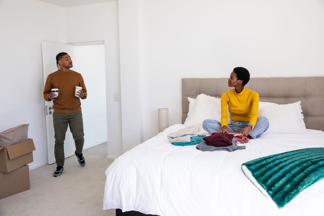 Young Couple Relaxing While Folding Laundry in Cozy Bedroom