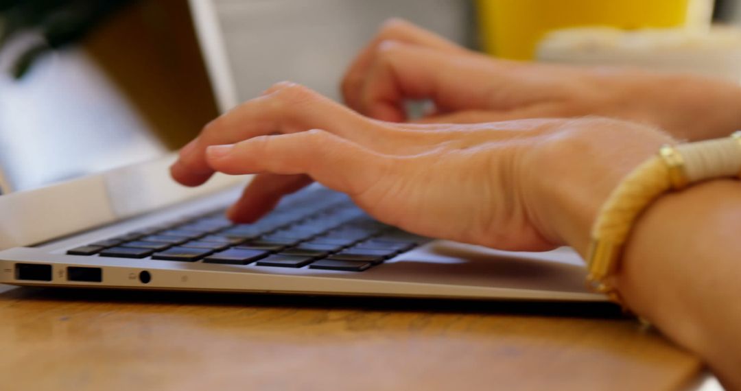 Hands Typing on Laptop Keyboard in Modern Workspace
