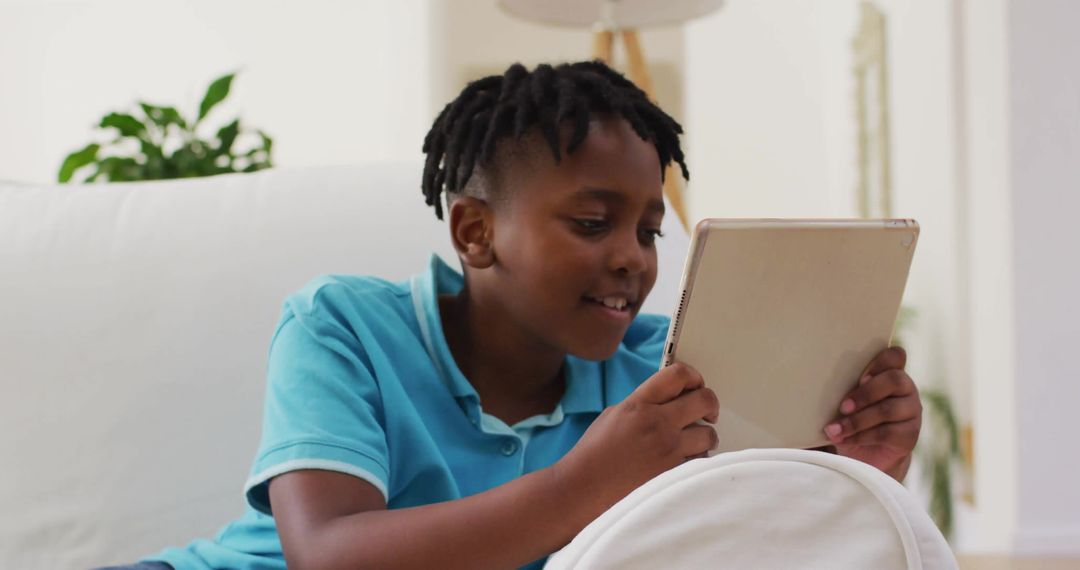 Young Boy Relaxing on Sofa Using Tablet at Home