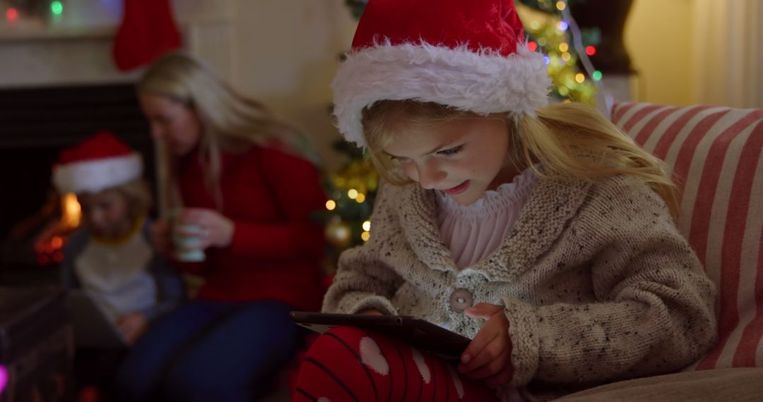 Young Girl in Santa Hat Enjoying Digital Tablet During Christmas - Free Images, Stock Photos and Pictures on Pikwizard.com