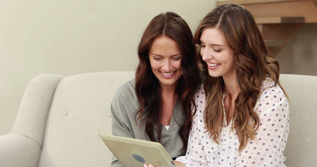 Two Young Women Sharing a Digital Tablet on the Sofa - Free Images, Stock Photos and Pictures on Pikwizard.com