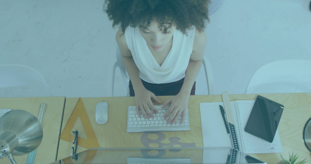 Overhead view creative professional typing at minimalist wooden desk with tablet and sketch tools