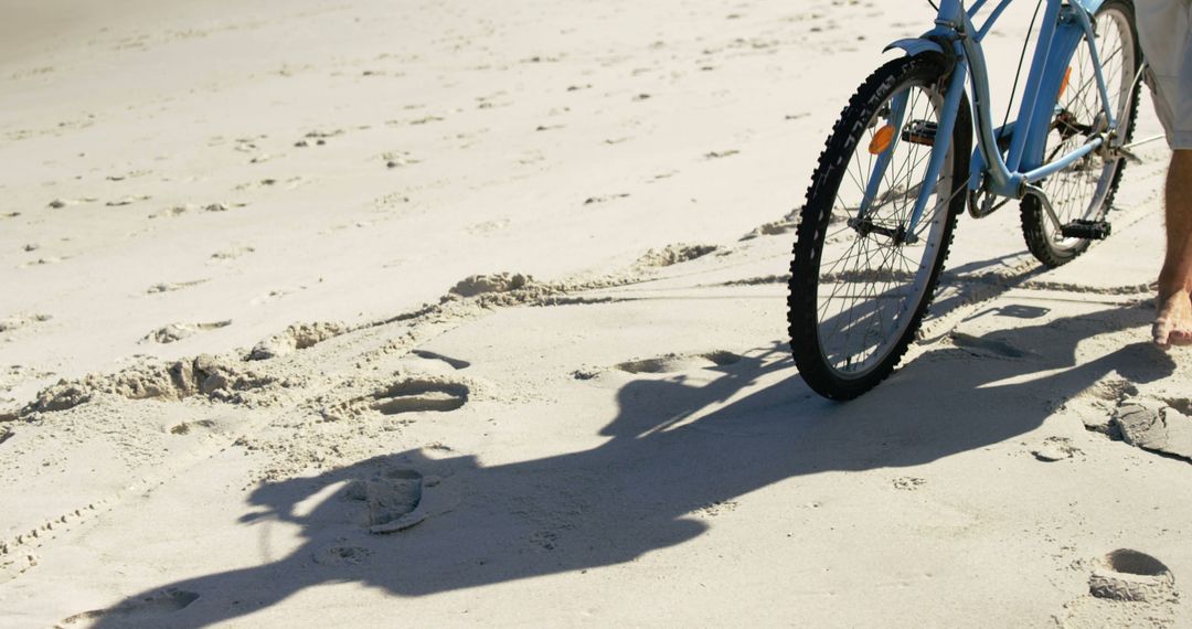 Bicycle Tire Marks on Sandy Beach with Bike and Person Walking - Free Images, Stock Photos and Pictures on Pikwizard.com