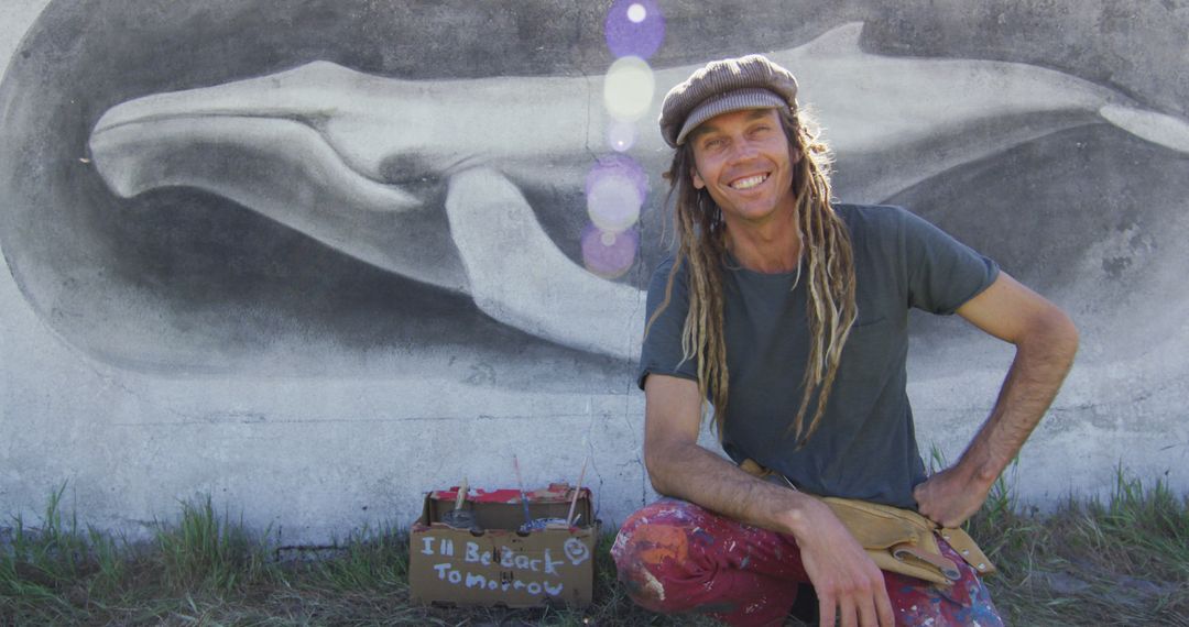 Street artist with dreadlocks posing near whale mural - Free Images, Stock Photos and Pictures on Pikwizard.com