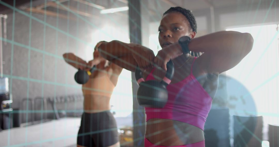 Women performing kettlebell upright rows in sunlit gym studio for strength and conditioning