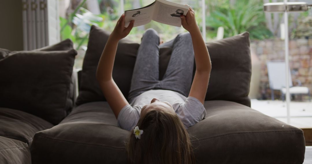 Girl Relaxing on Sofa Reading Book in Cozy Living Room - Free Images, Stock Photos and Pictures on Pikwizard.com