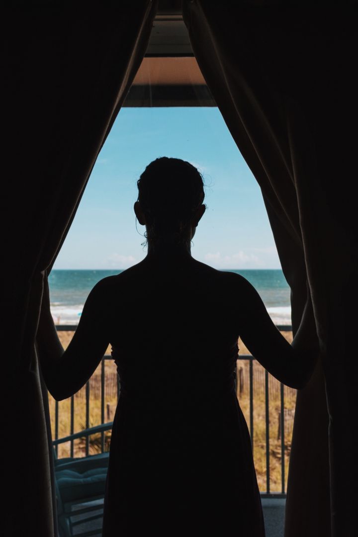 Silhouette of Woman Looking at Ocean Through Window Curtains - Free Images, Stock Photos and Pictures on Pikwizard.com