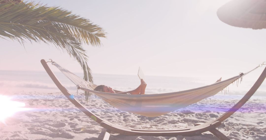 Woman Relaxing in Beach Hammock under Palm Tree