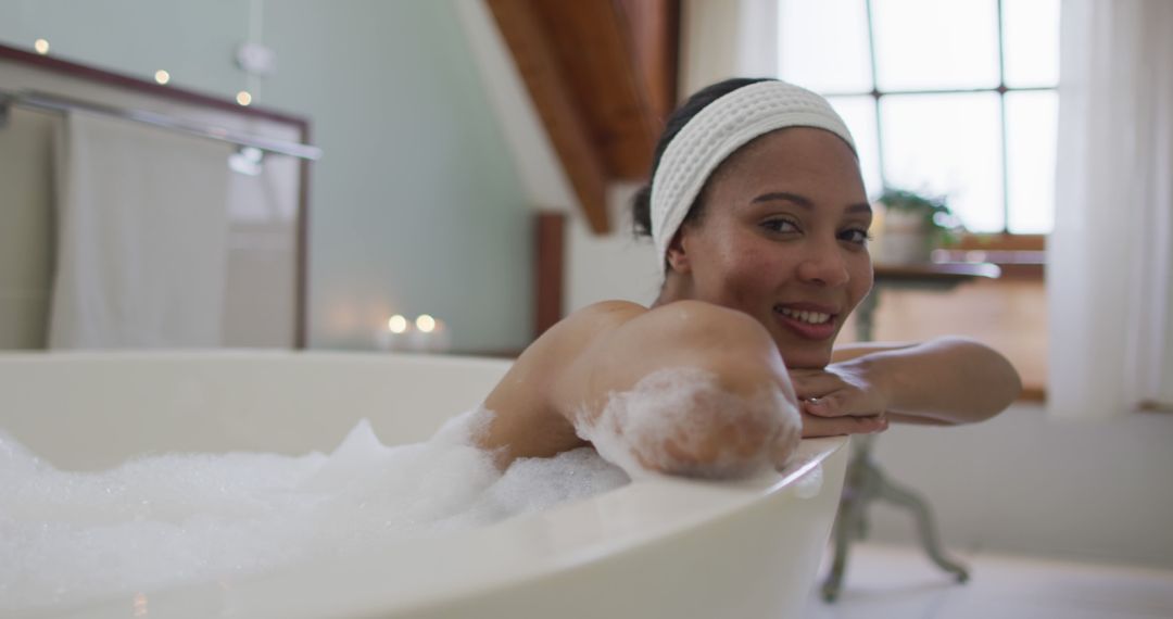 Portrait of biracial woman taking a bath looking at camera and smiling - Free Images, Stock Photos and Pictures on Pikwizard.com