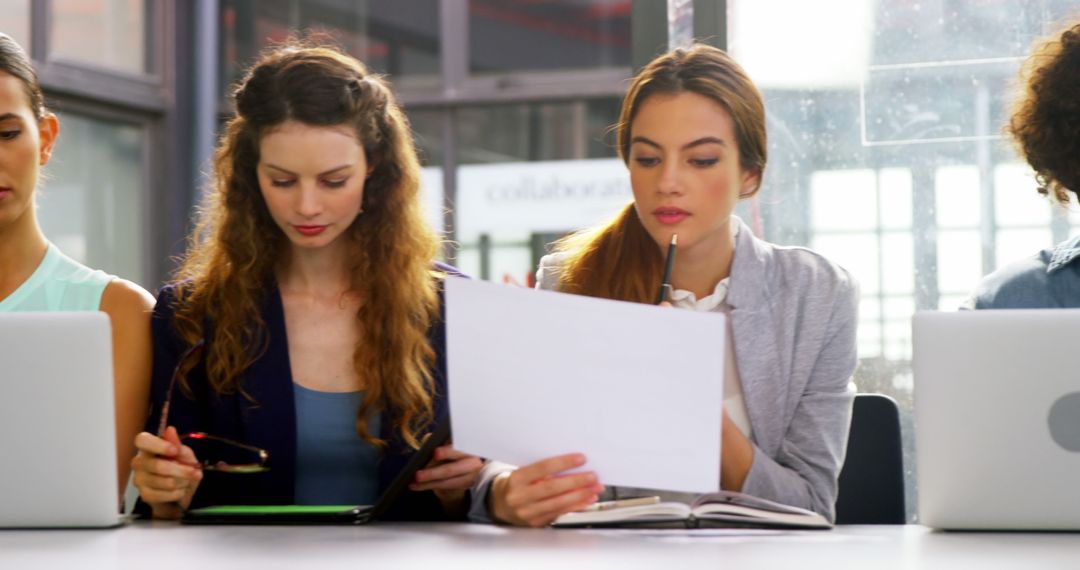 Young Professionals Collaborating on Digital Devices in Modern Office Setting