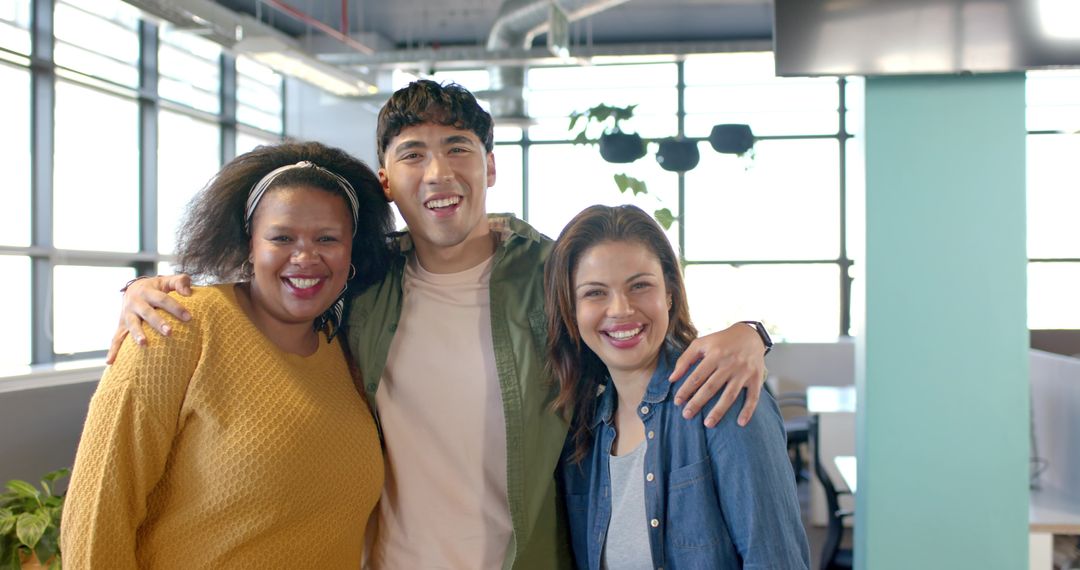 Diverse coworkers smiling and linking arms in sunlit modern open-plan office with plants