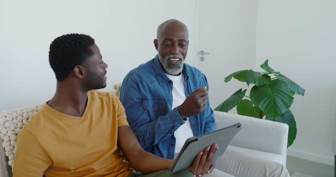 Father and Son Bonding Over Tablet at Home during Conversation