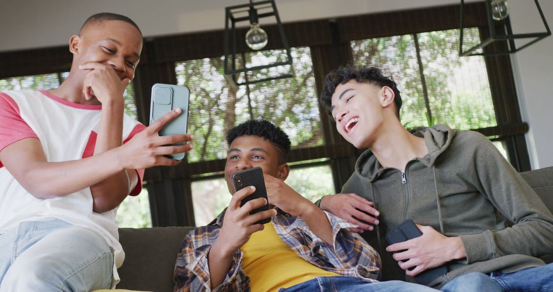 Teenagers Laughing Together While Using Smartphones at Home - Free Images, Stock Photos and Pictures on Pikwizard.com