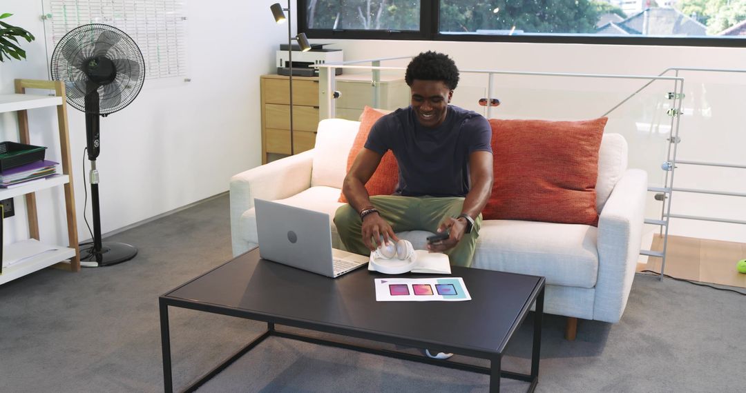 Man on Sofa with Laptop and Smartphone in Modern Home Workspace