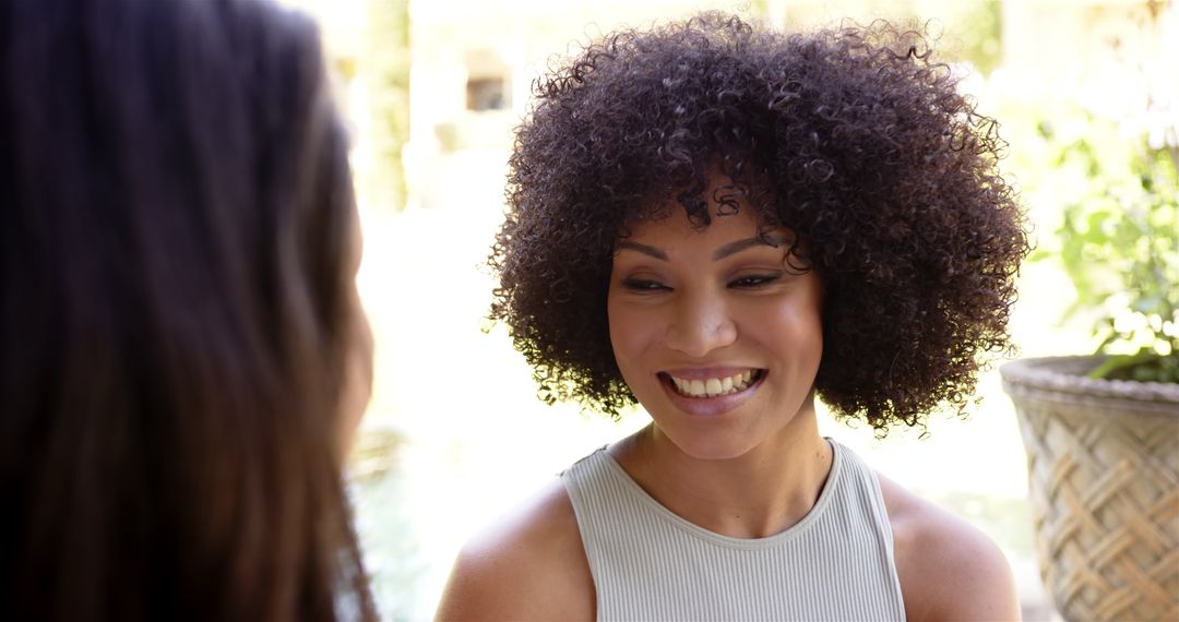 Smiling Woman with Curly Hair Engaging in Outdoor Conversation