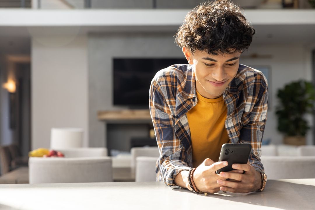 Young Man Using Smartphone in Modern Home Kitchen