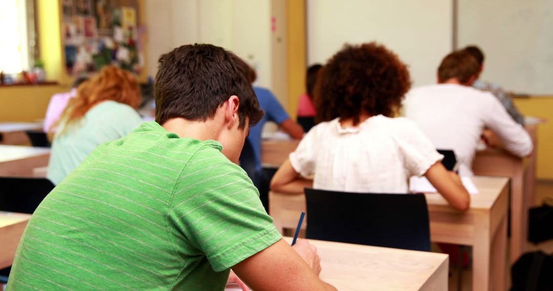 Students Taking Exam in Classroom with Focus on Male Student in Green Shirt - Free Images, Stock Photos and Pictures on Pikwizard.com