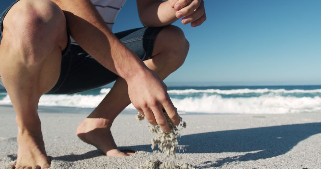 Person Kneeling on Beach Sifting Sand on Sunny Day - Free Images, Stock Photos and Pictures on Pikwizard.com