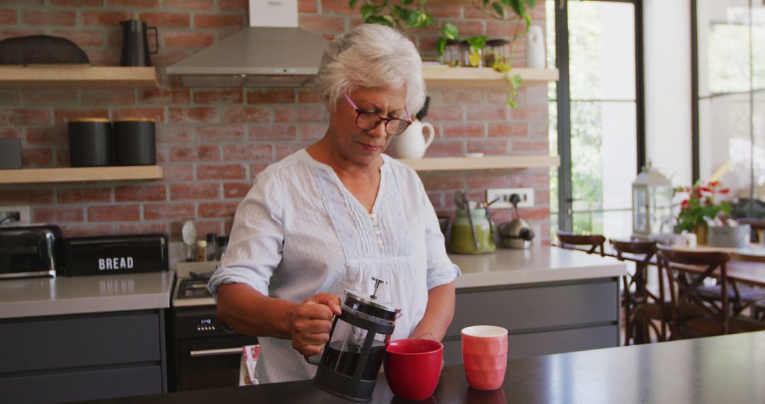 Senior Woman Pouring Coffee into Mug in Modern Kitchen - Free Images, Stock Photos and Pictures on Pikwizard.com