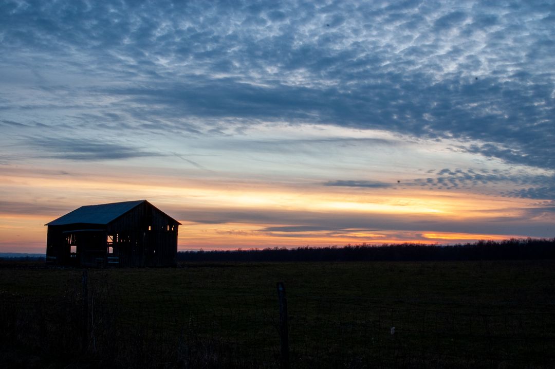Rustic Farmhouse Silhouette Against a Dramatic Sunset