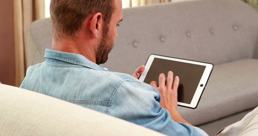 Man Using Tablet in Living Room - Free Images, Stock Photos and Pictures on Pikwizard.com