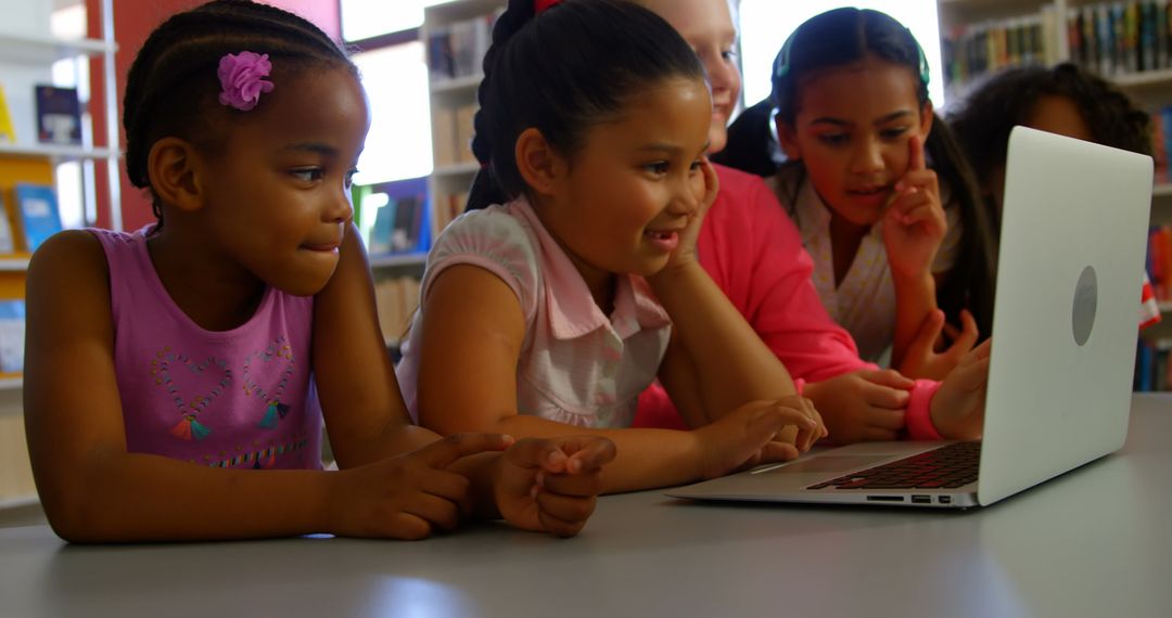 Diverse Schoolchildren Collaborating on Laptop in Library