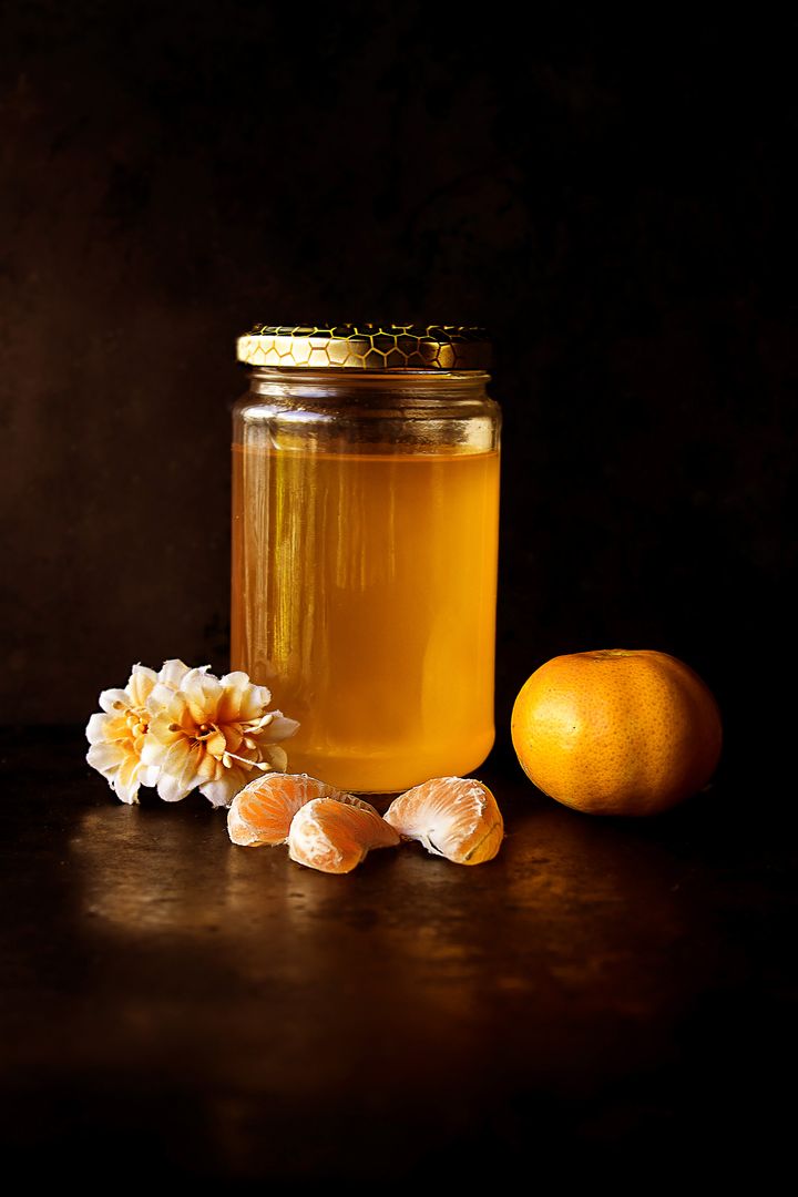 Jar of Honey with Tangerine and Blossoms on Dark Background