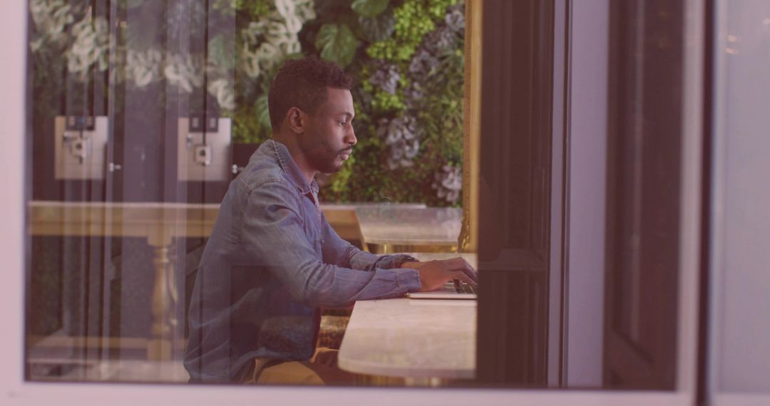 Focused Man Typing on Laptop in Modern Urban Workspace