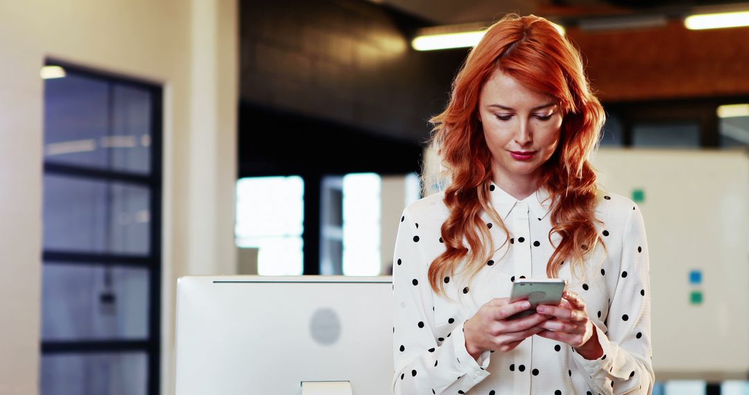 Young Woman with Red Hair Using Smartphone in Modern Office - Free Images, Stock Photos and Pictures on Pikwizard.com