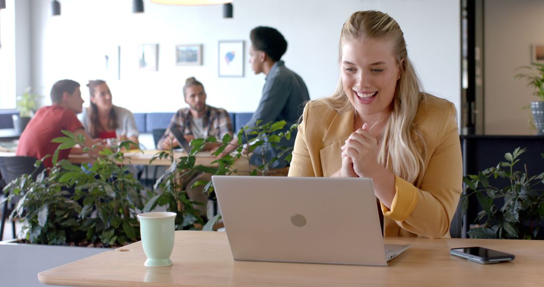 Excited Woman Having Video Call in Modern Office with Colleagues in Background - Free Images, Stock Photos and Pictures on Pikwizard.com