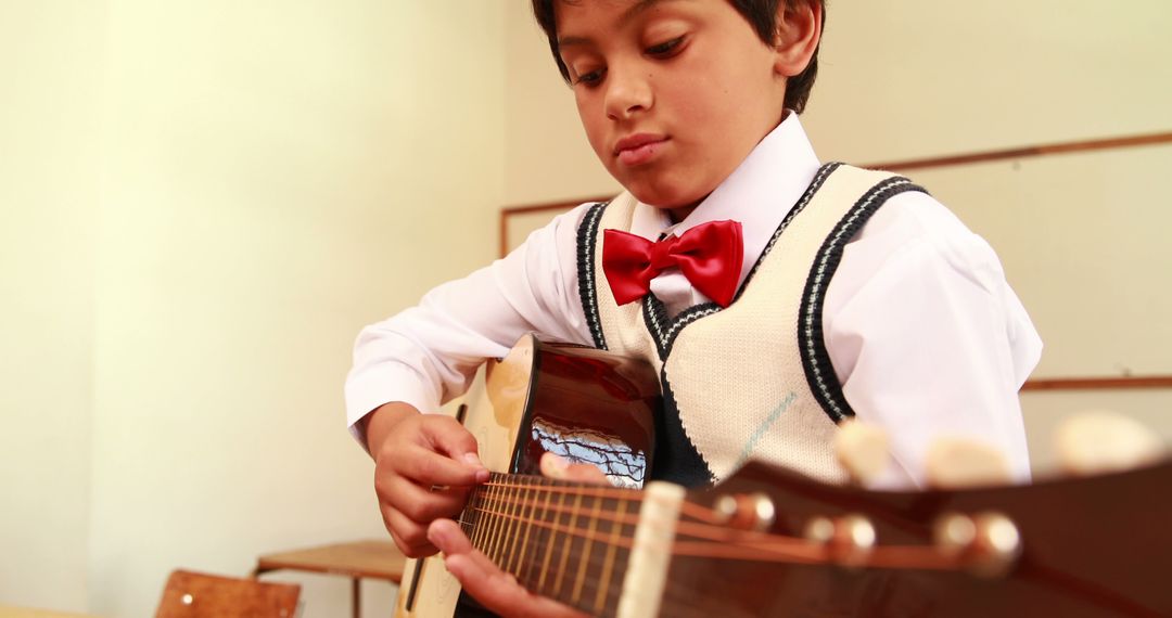 Young Student Playing Guitar in Classroom with Focused Expression