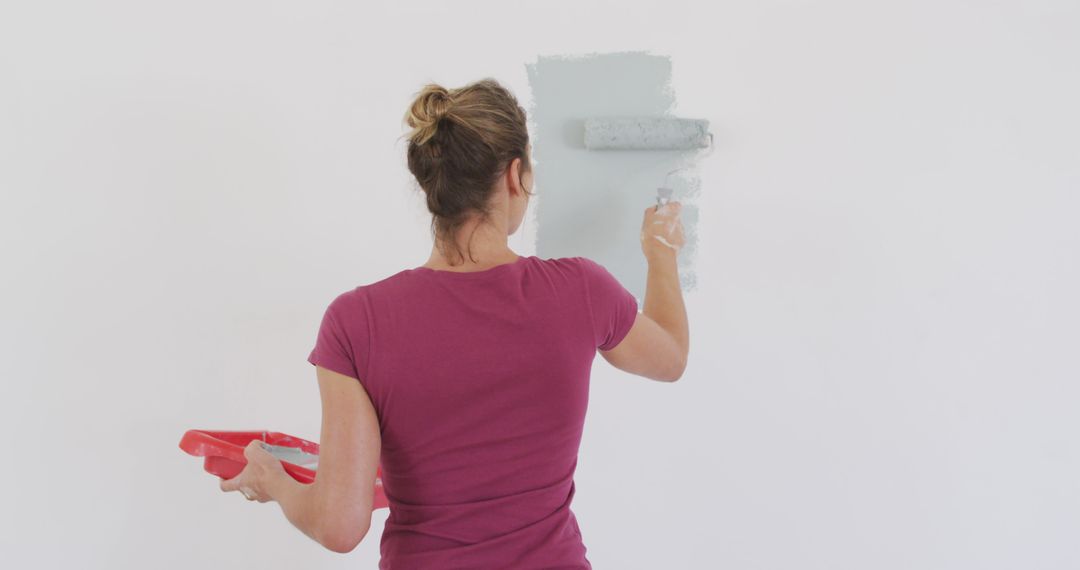 Caucasian woman painting wall with gray paint - Free Images, Stock Photos and Pictures on Pikwizard.com