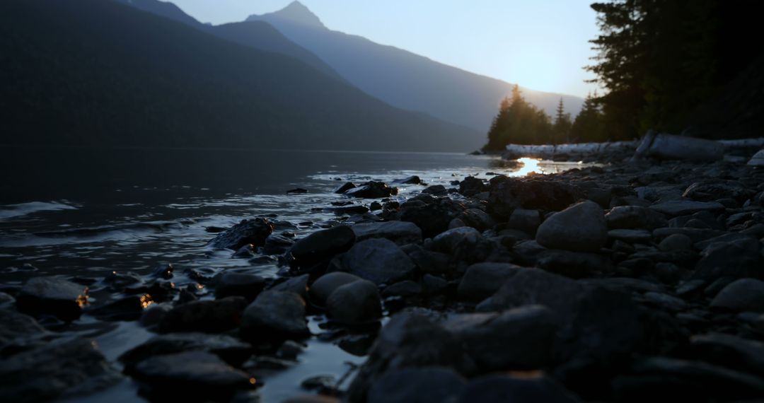 Peaceful Sunset by Rocky Lakeshore in Mountainous Landscape - Free Images, Stock Photos and Pictures on Pikwizard.com