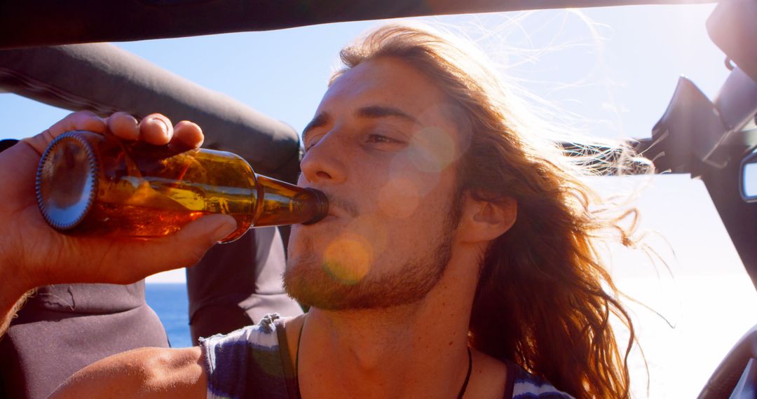 Young Man Drinking Beer on Sunny Road Trip - Free Images, Stock Photos and Pictures on Pikwizard.com