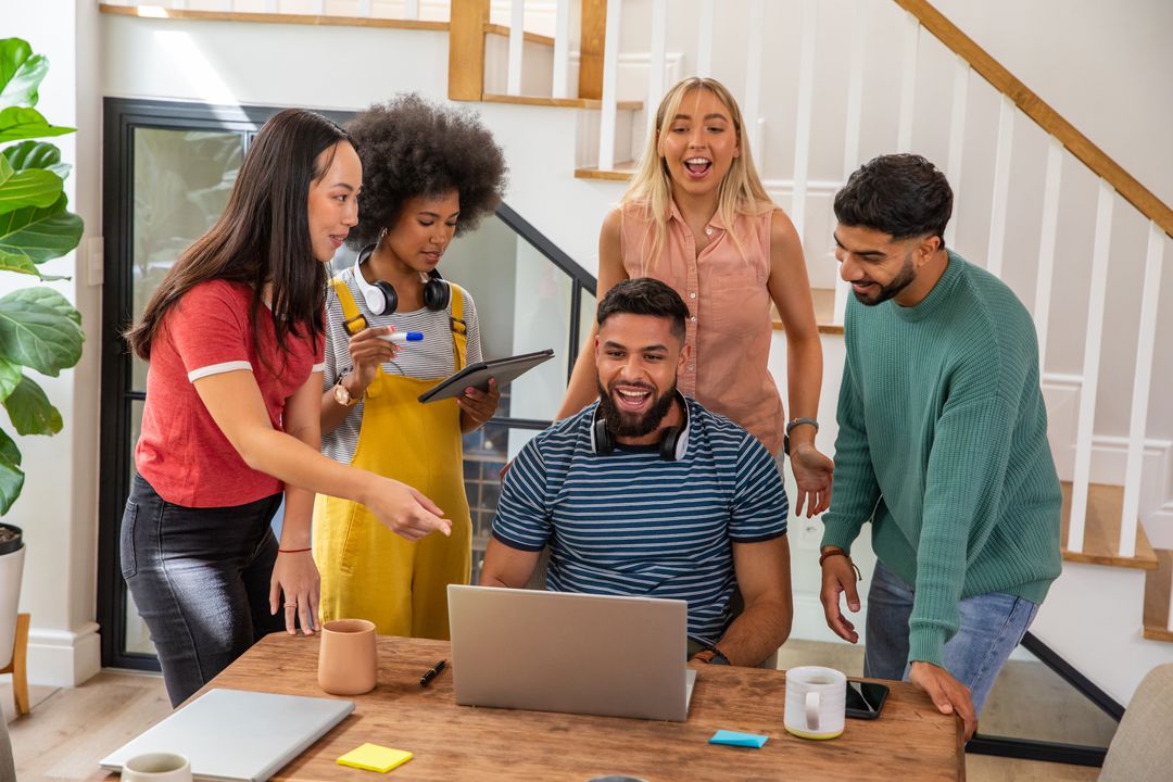 Diverse Team Brainstorming Around Laptop in Modern Home Office
