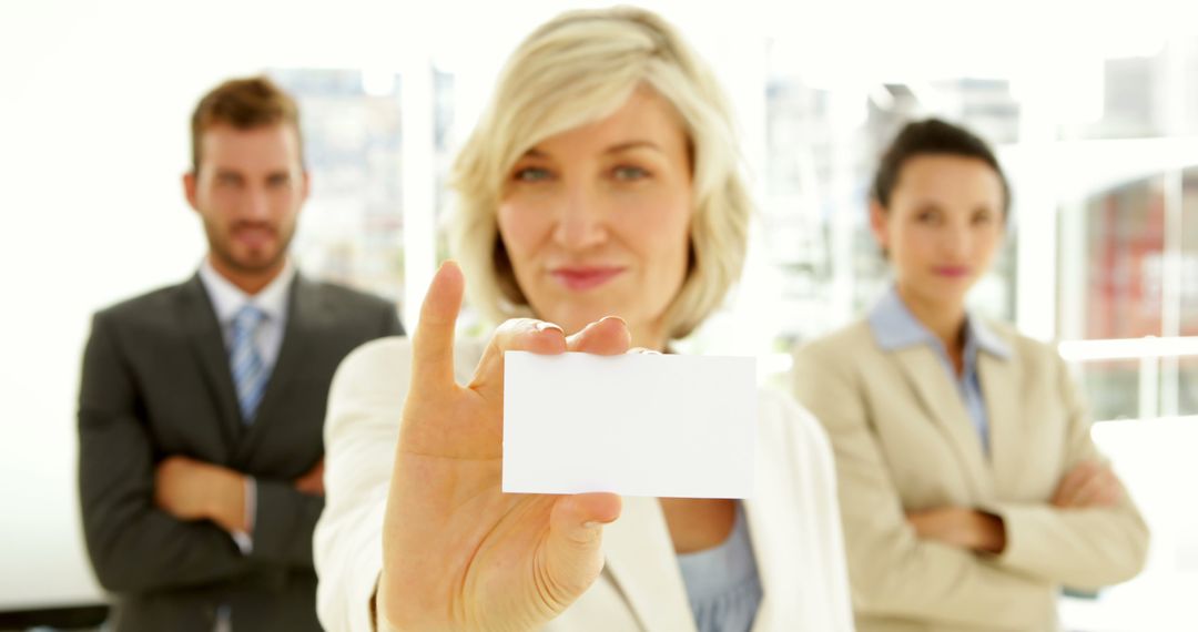 Confident Businesswoman Holding Blank Card with Colleagues in Background - Free Images, Stock Photos and Pictures on Pikwizard.com