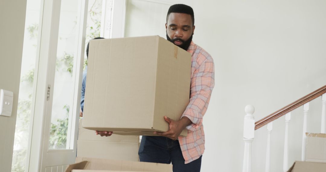 Busy african american couple moving house and holding cartons - Free Images, Stock Photos and Pictures on Pikwizard.com