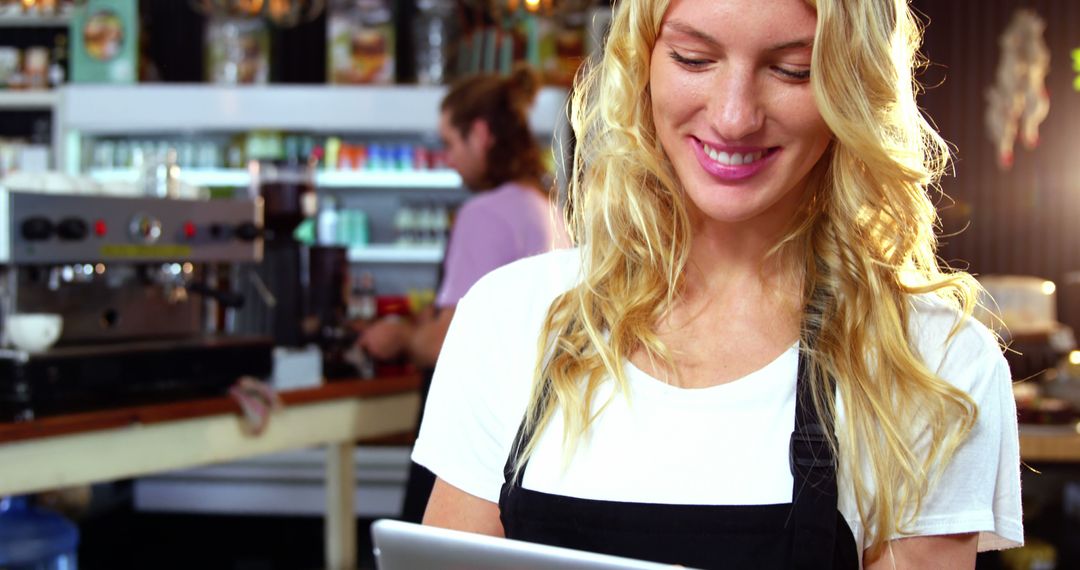 Blonde Barista Smiling and Using Digital Tablet in Café - Free Images, Stock Photos and Pictures on Pikwizard.com