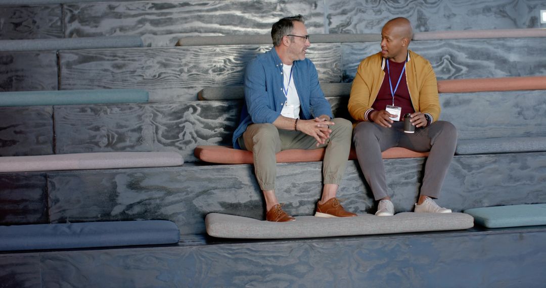 Diverse Coworkers Chatting on Tiered Seating in Modern Office Lounge with Cushions