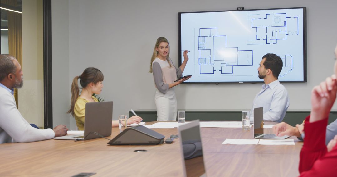 Mixed Team of Professionals Analyzing Building Plans in Modern Conference Room - Free Images, Stock Photos and Pictures on Pikwizard.com