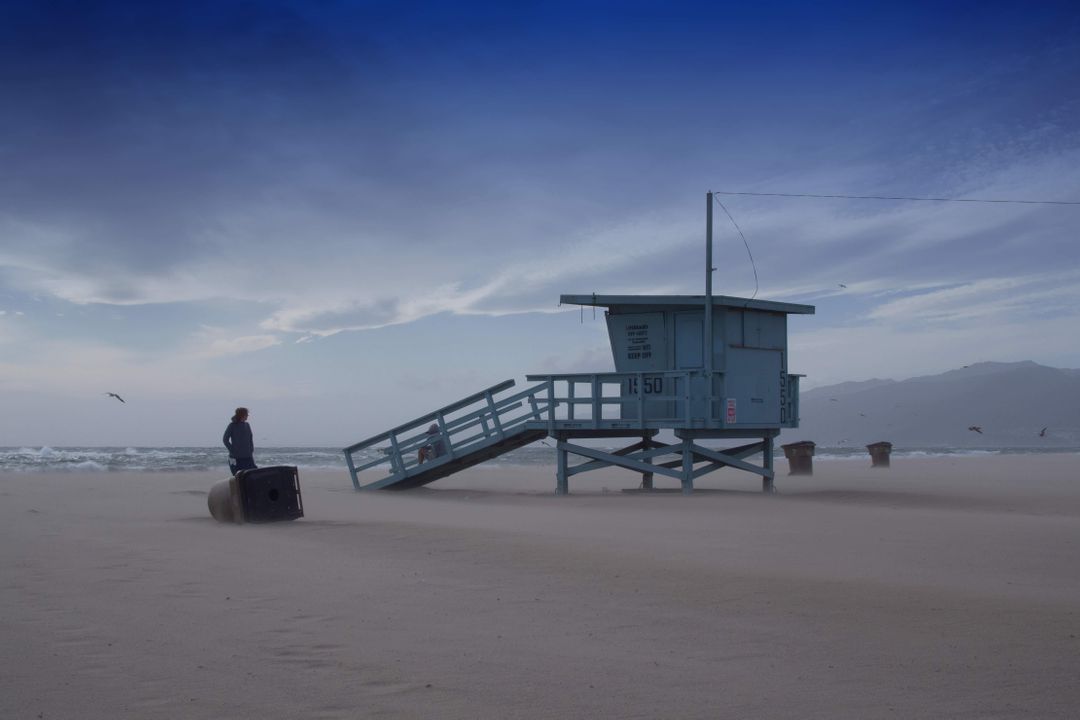 Empty Beach with Lifeguard Tower and Lone Figure at Sunset - Free Images, Stock Photos and Pictures on Pikwizard.com