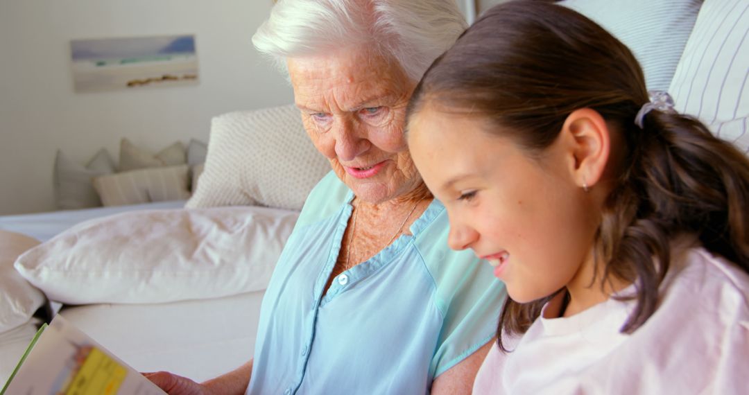 Grandmother Reading Book with Young Granddaughter at Home - Free Images, Stock Photos and Pictures on Pikwizard.com