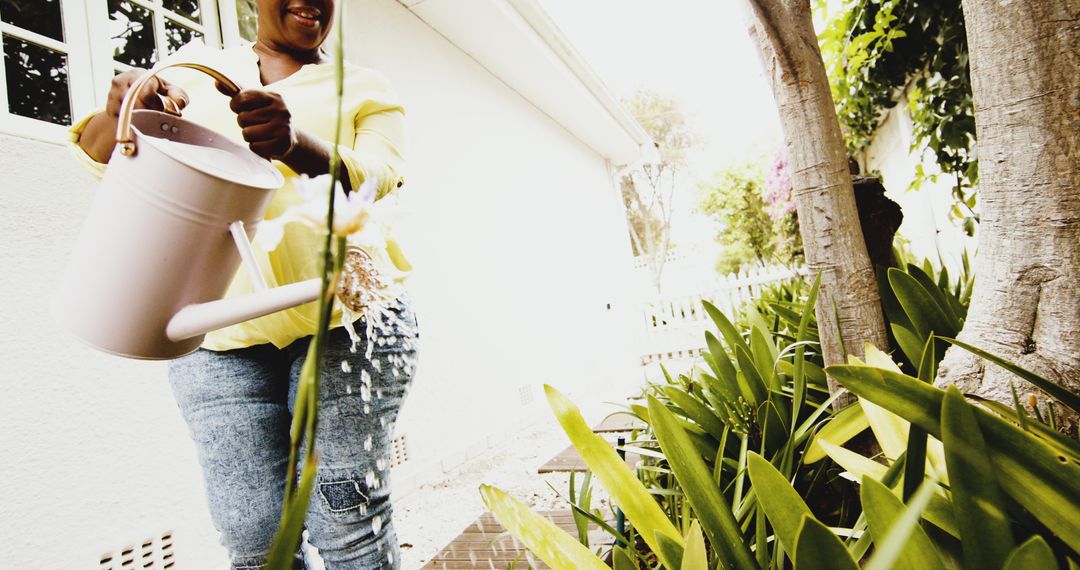 Smiling Woman Watering Plants Outdoors in Garden - Free Images, Stock Photos and Pictures on Pikwizard.com