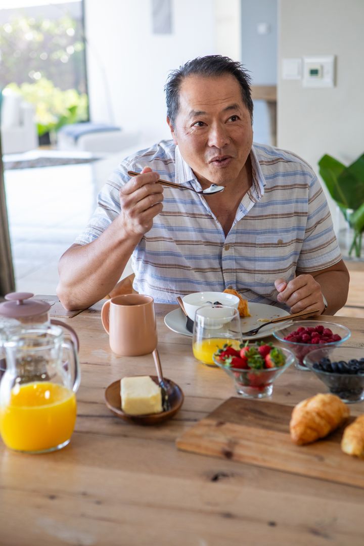Man Enjoying Breakfast with Orange Juice and Croissant at Dining Table
