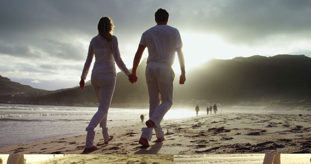 A young Caucasian couple walks hand in hand along a sandy beach at sunset, with copy space - Free Images, Stock Photos and Pictures on Pikwizard.com