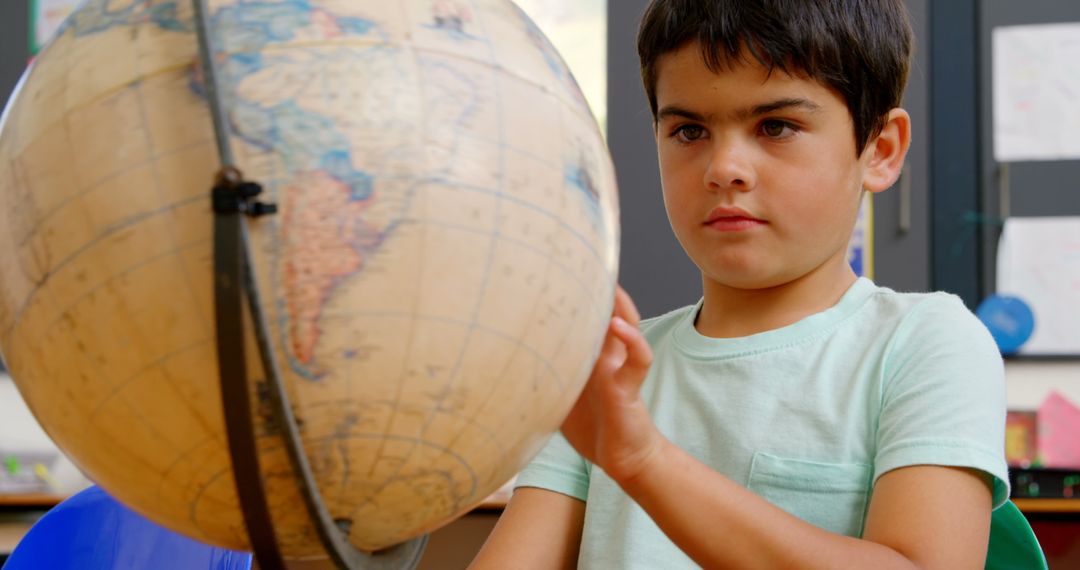 Schoolboy Engaged with Spinning Globe in Classroom Setting