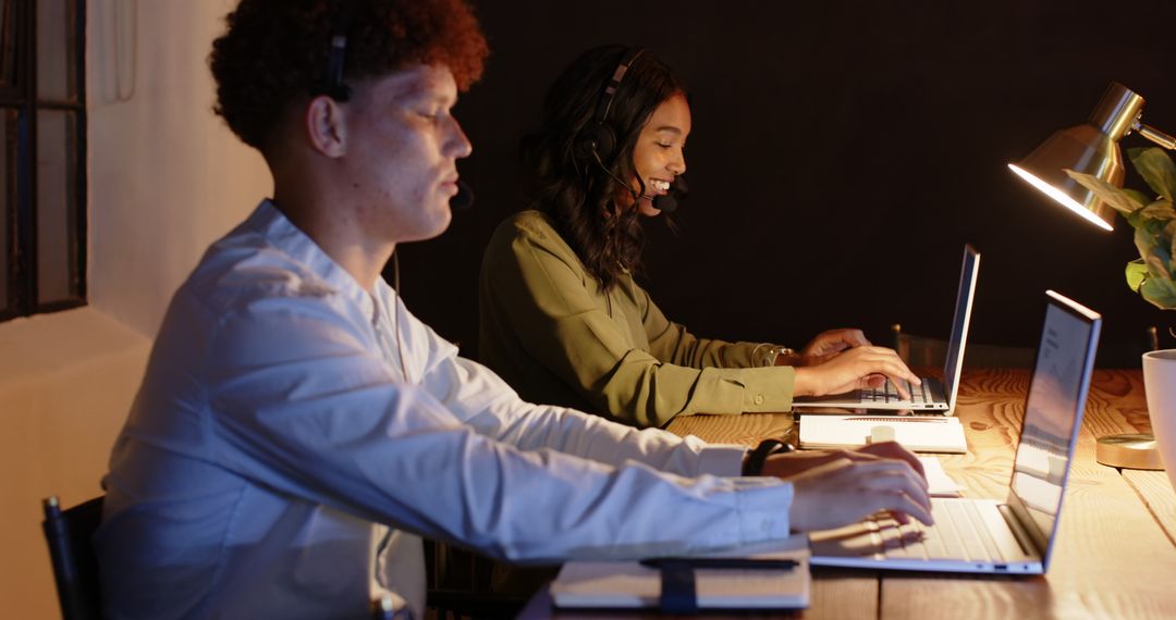 Diverse Colleagues Collaborating in Office at Night Using Laptops